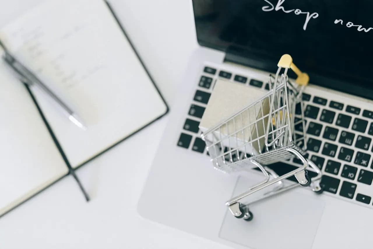 A miniature shopping cart on a laptop that shows a shop page